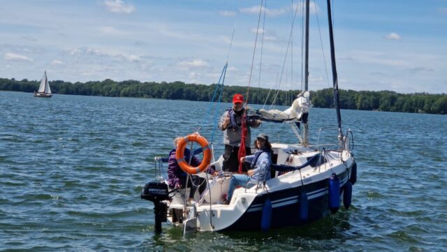 Podczas szkolenia na patent żeglarza instruktor wraz z kursantami na kursie żeglarskim uczą się klarować jacht. Żaglówka płynie na jeziorze Drawsko w Czaplinku.