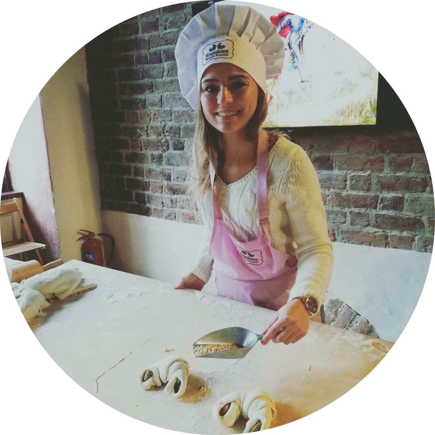 Dziewczyna w czapce szefa kuchni, przygotowuje rogala świętomarcińskiego w Poznaniu.