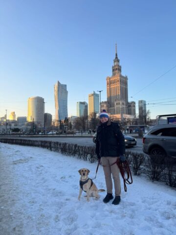 wycieczka szkona do warszawy Mężczyzna z psem labradorem biszkoptowym na tle Pałacu Kultury w Warszawie